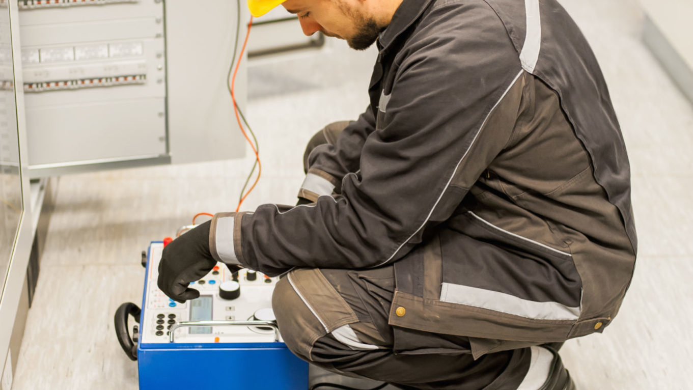Electrician engineer tests system with relay test set equipment